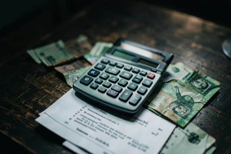 Uma calculadora e notas de dinheiro sobre documentos legais em uma mesa.