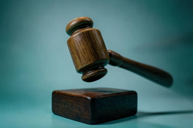 Um martelo de juiz batendo sobre um bloco de madeira em um tribunal.