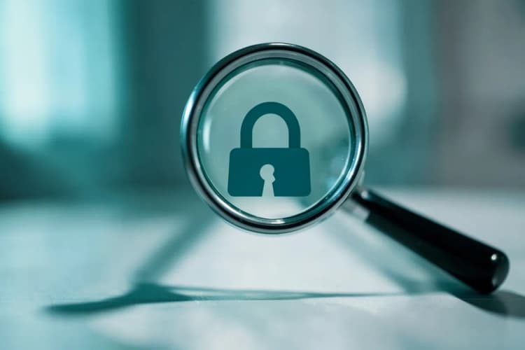 Uma lupa examinando um ícone de cadeado quebrado em um fundo digital desfocado.
