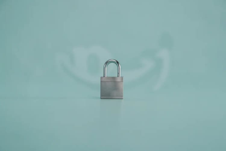 cadeado fechado sobre um cartão de crédito com o logo da Amazon desfocado ao fundo