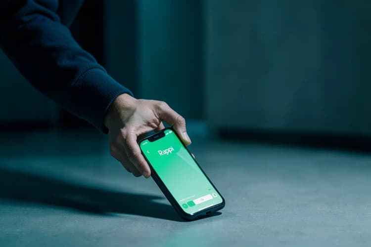 Uma pessoa jogando um celular no chão em frustração, com o aplicativo Rappi visível na tela.
