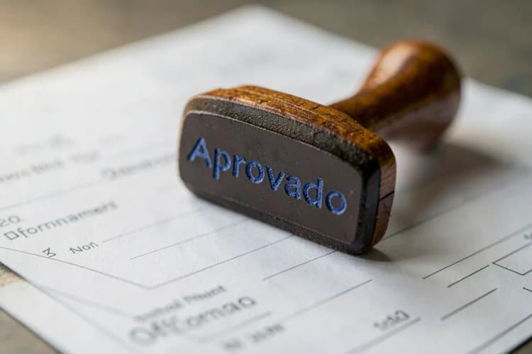 Um carimbo de borracha com a palavra "Aprovado" em tinta azul sobre um formulário oficial em papel.