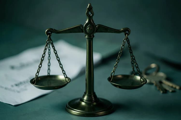 Uma balança de justiça equilibrada sobre um fundo desfocado de um contrato e chaves.