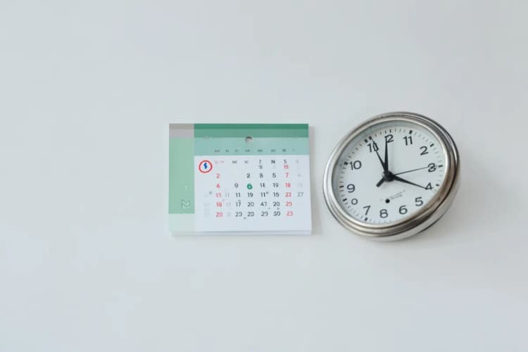 Um calendário com a data marcada em vermelho e um relógio ao lado.