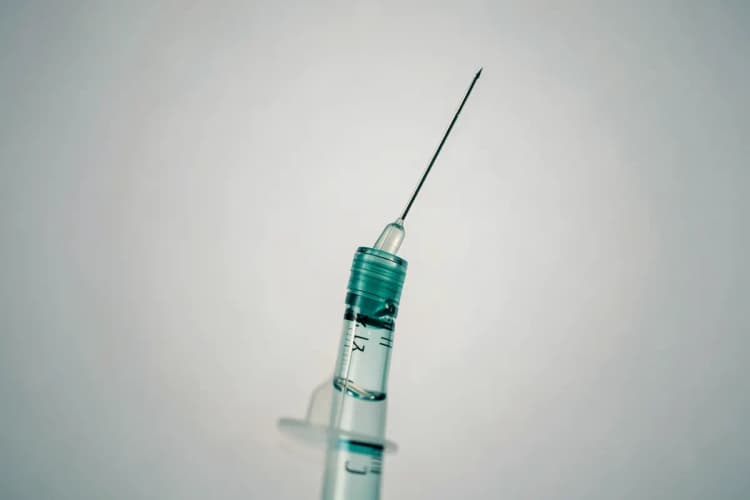 Uma seringa de Clexane (enoxaparina sódica) sendo preparada para injeção, com foco na agulha e no líquido.
