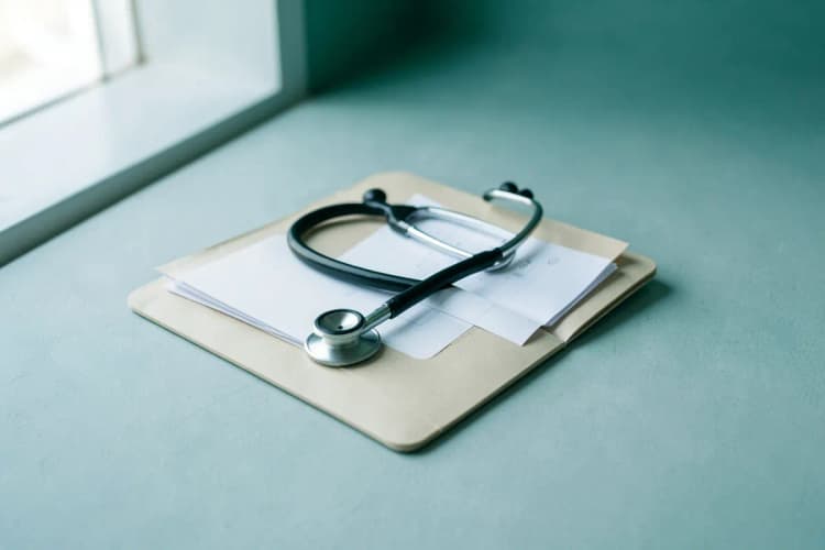 Um estetoscópio sobre um prontuário médico aberto, simbolizando a decisão entre plano de saúde e SUS.