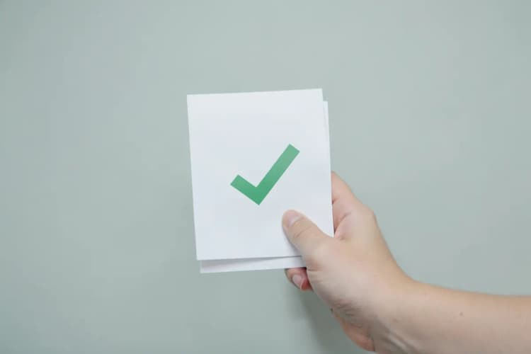 Uma pessoa segurando um documento com um símbolo de check mark, representando direitos garantidos.