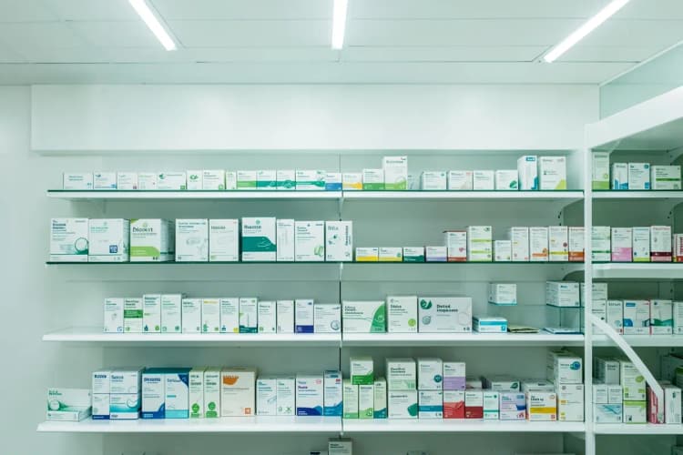 Uma variedade de medicamentos genéricos e de marca em prateleiras de farmácia.