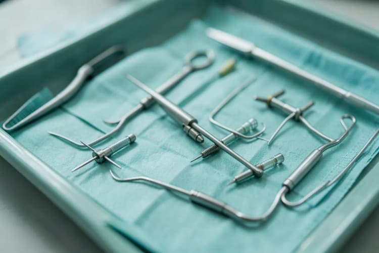 Conjunto de ferramentas cirúrgicas e implantes de prótese peniana organizados em uma bandeja esterilizada.