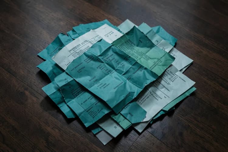 Uma pilha de contratos de papel rasgados e amassados em um chão de madeira escura.
